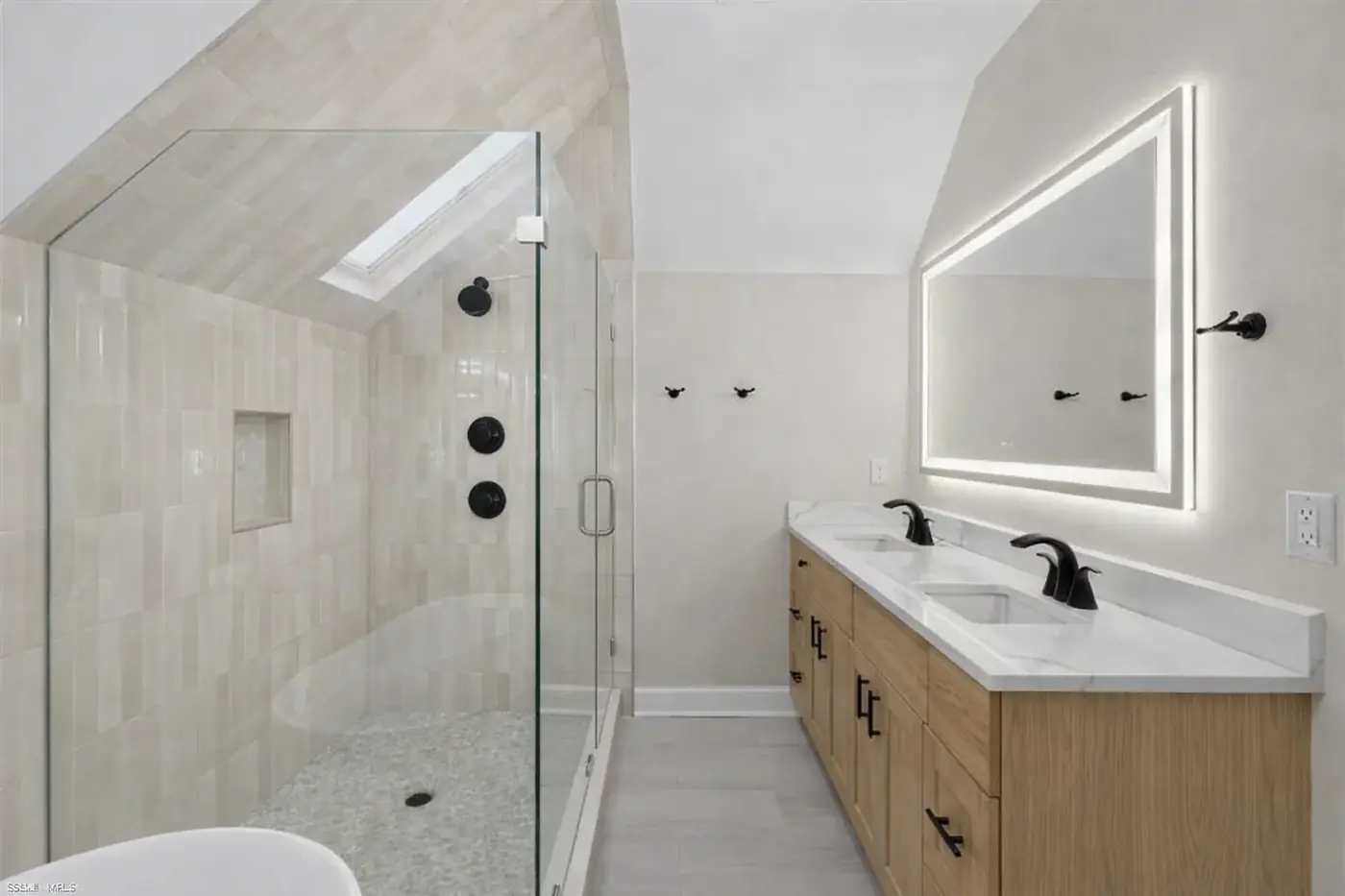 Modern bathroom with tiled shower, floating vanity and warm brass fixtures